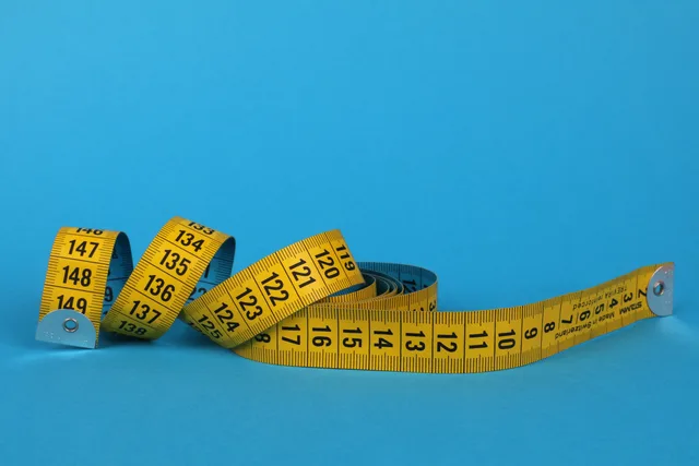 Coiled yellow measuring tape against a vibrant blue background, offering ample copy space. Kundenbindungsmaßnahmen messen