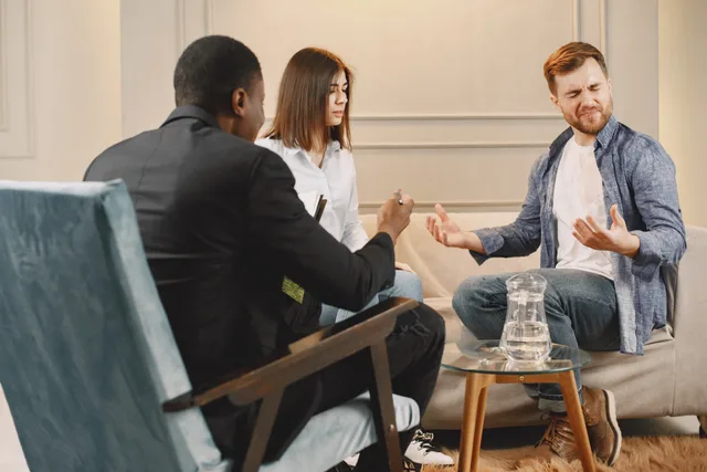 A diverse couple in a serious conversation with a lawyer during a meeting in an office setting. Offene Kundenprobleme vor einem Zusatzangebot klären